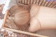 A woman laying in a wooden basket with her back to the camera.