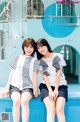 A couple of women sitting next to each other on a blue bench.
