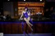 A woman in a purple outfit sitting on a bar.