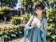 A woman in a blue kimono standing in a garden.