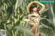 A naked woman in a straw hat standing in a corn field.