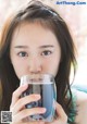 A woman holding a glass of water in her hand.