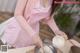 A woman in a pink apron is preparing food on a table.